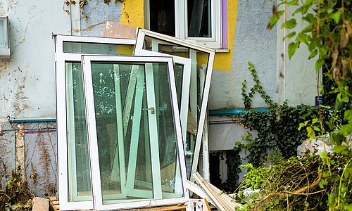 Kaputte Fenster die an sanierungsbedürftigem Haus lehnen